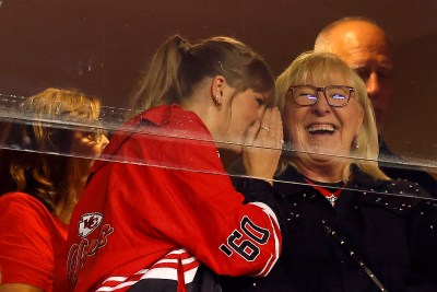 Donna Kelce laughs as Taylor Swift whispers something into her ear at a Chiefs game.